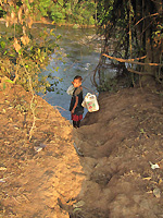 子どもが汲んだ水を担いで運んでいる